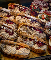 Fototapeta premium Delicious eclairs with coffee cream, walnuts and berry sauce.