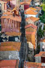 A row of houses with red roofs and brown walls. The houses are lined up in a row, with some of them having balconies. Scene is one of a quaint. Porto, Oporto, Portugal.