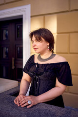 a medium-sized woman in a black corset near a theater with antique columns