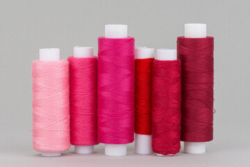 Red and pink thread spools on grey background