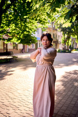  plus size woman in a peach fuzz dress walks through the morning city