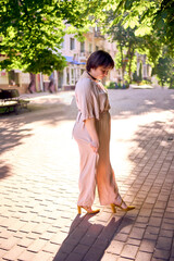 plus size woman in a peach fuzz dress walks through the morning city