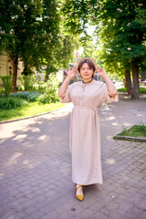 plus size woman in peach fuzz dress with hat having fun on morning city streets