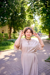plus size woman in peach fuzz dress with hat having fun on morning city streets