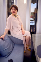 medium sized woman in peach fuzz dress with glass of water in restaurant
