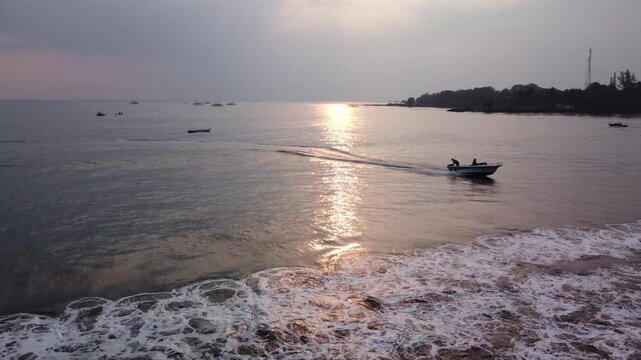 Cinematic drone of long tail speed boat at sunset and sunlight reflection in the sea. Carita Beach. Sunrise.