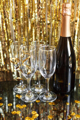 a bottle of champagne and glasses for champagne for christmas, new year, party, wedding celebration with gold red confetti and decoration
