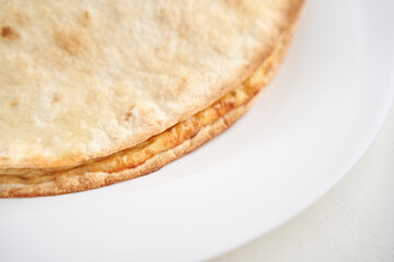 Delicious cheese quesadilla on white plate perfect for mexican cuisine themes and close-up photography inspiration.