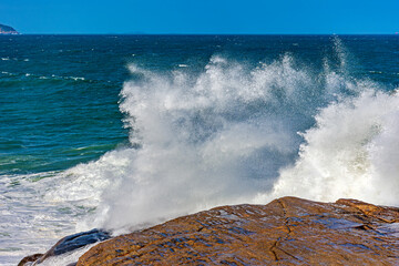 Sea water splashing after a wave crashes hard against the rocks on Ipanema beach in Rio de Janeiro