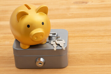 Saving and protecting your money with a gold piggy bank safety lockbox on a desk