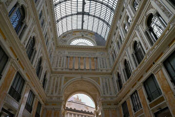 Vue intérieure d'une arche de l'entrée de la galerie Umberto I de Naples avec une verrière et un aperçu du théâtre San Carlo