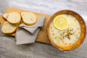 Cuisine Ideas. Brown Clay Bowl WIth Italian Lemon Chicken Orzo Soup With Freshly Baked White Bread Over Wooden Background