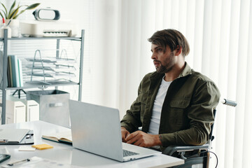 Fototapeta premium Businessman with disability working on laptop at his workplace in office