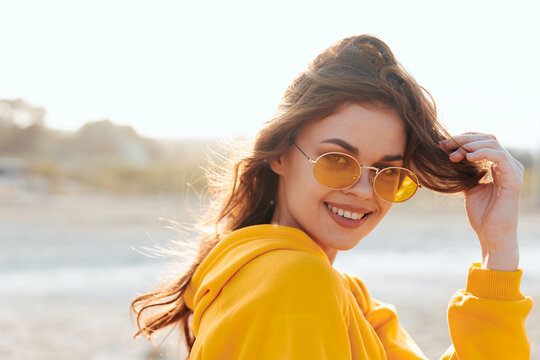 Woman in yellow sweater and sunglasses enjoying sunny day at the beach - Powered by Adobe