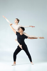 Dance Ideas. Flexible Passionate International Sportive Couple of Asian Man and Caucasian Woman Performing As Ballet Dancers On Grey in Studio During Suppots As Classical Dance © danmorgan12