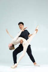 Couple of Asian Man and Caucasian Woman Performing As Ballet Dancers On Grey in Studio During Suppots As Classical Dance © danmorgan12