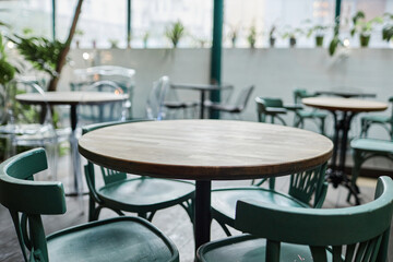 Medium close up of round wooden table with turquoise chairs in cafe