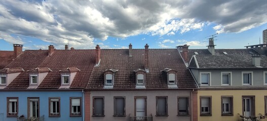 illustration of an urban landscape, a row of buildings with differently colored roofs in the city, under a cloudy sky 