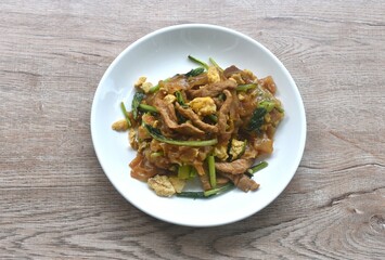 stir fried large rice noodles with slice fermenting pork and Chinese kale dressing black sweet soybean sauce on plate