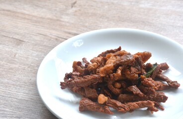 fried crispy salty fermenting beef meat with pandan and herb on plate 
