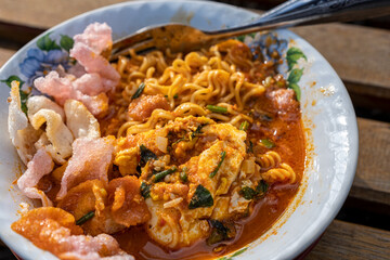 Spicy Noodle Soup with Egg, Crispy Crackers, and Herbs