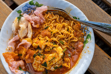 Partially Eaten Bowl of Noodles with Crispy Crackers and Egg