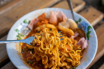 Close-up of Fork Lifting Noodles from Bowl of Spicy Food
