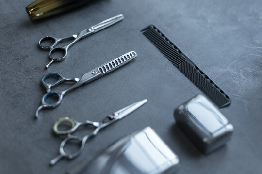 Haircutting tool set: scissors, tremer, shaving machine and comb lie on a gray background. Barbershop, concept