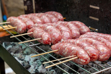 Raw sausages skewers grilling on barbecue for summer lunch