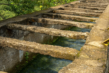 Mountain water flows in an irrigation building left over from the Dutch colonial era on a rotten...
