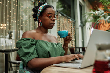 Young African American woman drinking hot black tea while checking social networks
