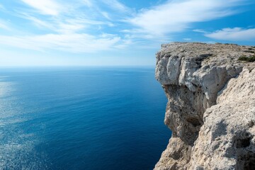 This image captures a stunning ocean view with crystal clear blue waters and rugged coastal cliffs under a bright, lightly clouded sky, showcasing the beauty of nature's landscape. - Powered by Adobe