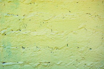 Retro wall painted with modern bright yellow green paint. Ugly arranged bricks on the wall.