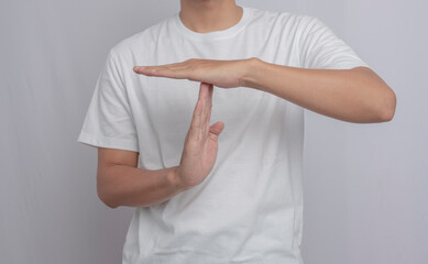 A young man with a beard in casual attire making a 'time out' or 'pause' gesture with his hands...