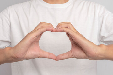 Beautiful human hand giving heart signal. Hand gesture forming a heart sign on an isolated white background. Beautiful hands of woman with copy space. Concept of love on the day of happiness.