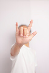 An Asian young man wearing a white t-shirt and making a hand gesture 