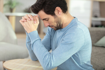 worried man praying at home