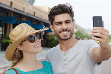 young couplet taking selfie in front of station