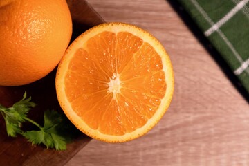 Top view of orange fruit with orange slices and leaves on a wooden table