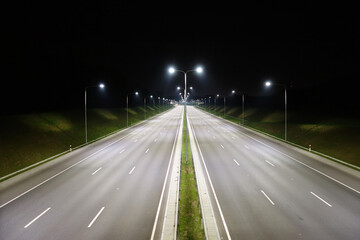 Empty Highway at Night with Streetlights and Green Embankments