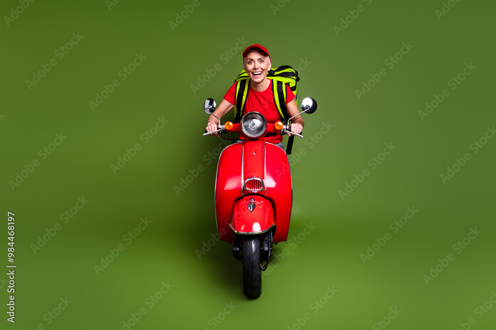 Sticker Full body photo of attractive mature lady delivery employee thermo bag scooter wear red uniform workwear isolated on khaki color background