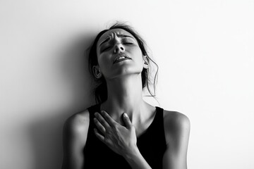 A person in a black and white artistic style photograph touches their neck while looking up, wearing a sleeveless top, evoking feelings of contemplation and introspection.