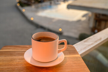 Black coffee in a mug on the background of the pool