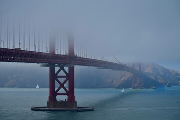 Golden Gate Bridge partially covered in fog with the San Francisco Bay in the background