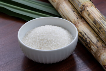 A simple yet elegant kitchen scene with a ceramic bowl filled with white sugar, cane, and cane leaves as a nod to its natural origins.