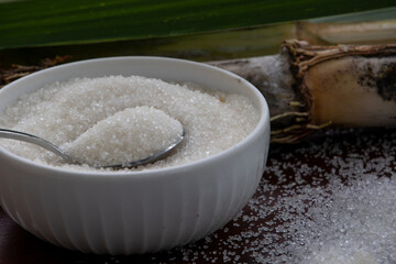 Granulated Sugar in a Bowl with Sugar Cane Decoration on Wooden Table