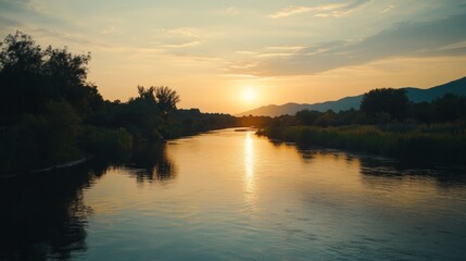 Obraz premium Tranquil River Sunset, a serene scene showcasing the calm waters reflecting warm hues of dusk, surrounded by lush greenery, embodying peace and natural beauty.