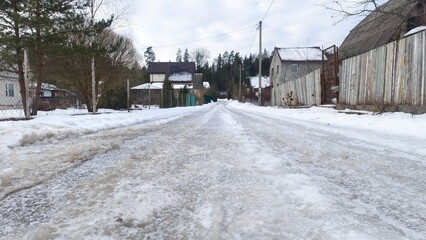 There is snow on the ground and roofs of the houses. There are wooden and metal mesh fences and...
