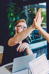 Successful male and female freelancers high five to each other and feeling good from well done work...