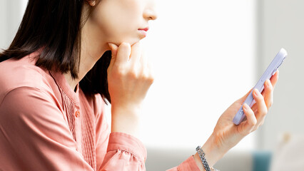スマホを見て考える若い女性の横顔